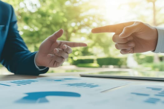 Two men are pointing at a piece of paper with graphs on it. One man is pointing to the left and the other is pointing to the right. Scene is serious and focused