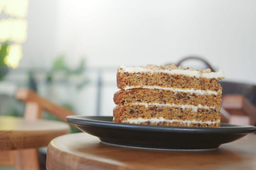 A slice of moist carrot cake is presented on a black plate.