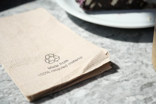 Recycled napkin rests on a marble table with dessert nearby.