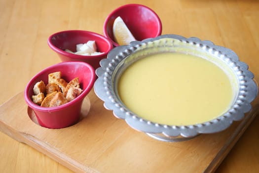 Lentil soup accompanied by toasted bread, cheese, and lemon slices.