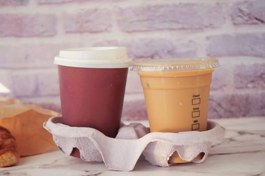 Two cups of coffee and a pastry placed on a table in a cafe environment.