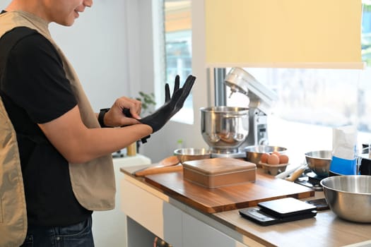 Home baker wearing gloves before handling ingredients while baking cookies.