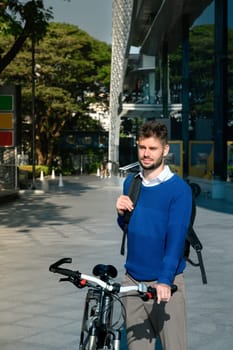Young caucasian man standing with his bicycle in a modern city. Sustainable Transportation concept.