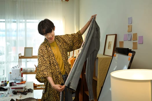 Young designer measuring denim for customization in a creative studio.