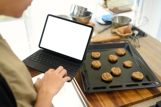 Baker checking recipe on digital tablet while preparing chocolate chip cookie dough.