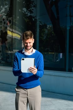 Smiling young entrepreneur using digital tablet in the city.