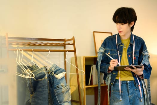 Creative designer using digital tablet working on new collection in a stylish studio.