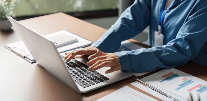 A business professional using a laptop to analyze reports and manage finances in a modern office environment.