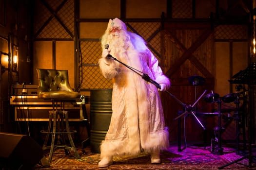 Santa Claus in white costume singing in microphone in bar while standing on stage