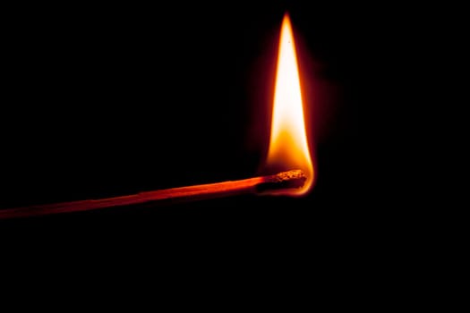 Side view of a burning match isolated on black.