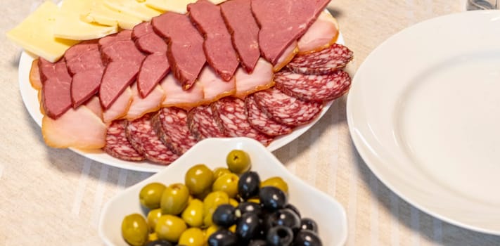 Shot of the table set up with assorted cut fresh vegetables, cold cuts, olives
