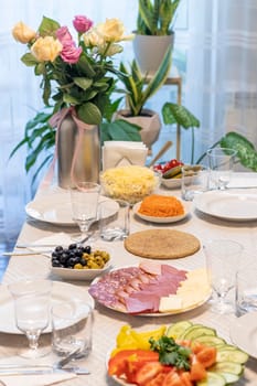 Shot of the table set up with assorted cut fresh vegetables, cold cuts, olives, salads.