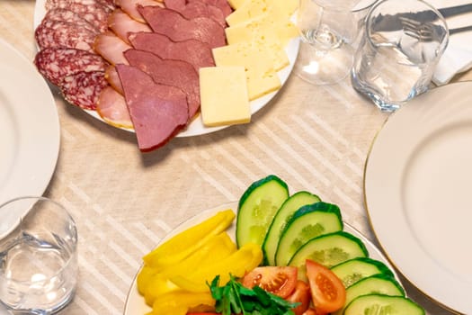 Shot of the table set up with assorted cut fresh vegetables, cold cuts, olives, salads.