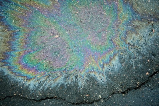 Cracked pavement with vibrant oil spill patterns.