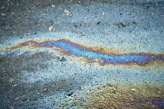 Vibrant oil slicks seen closely, showcasing a textured surface with a spectrum of colors on the asphalt