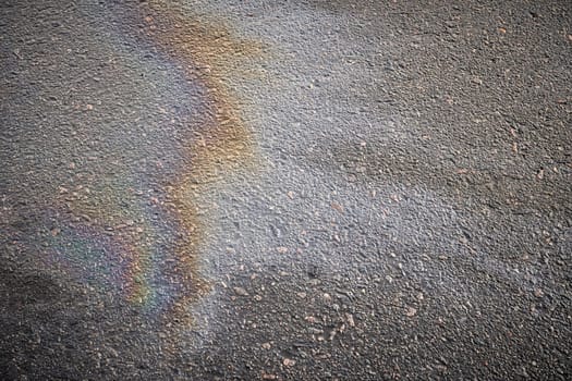 Detailed view of oil stains on the road surface, showcasing the vibrant colors of gasoline as a captivating texture