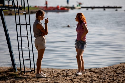 On a beautiful sunny day at the beach, two women are happily engaged in a lively conversation amidst gorgeous scenery