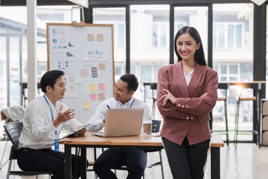 Portrait of a young businesswoman standing in an office where employees are working..