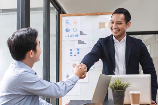 Two happy professional businessmen shaking hands after a successful financial deal at a meeting..