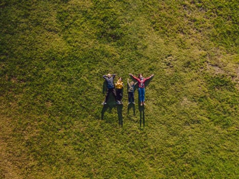 family top view. lying on the grass. sunny day. in green nature together. Aerial view Drone photography.