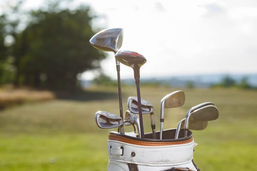 Golf clubs drivers over green field background.