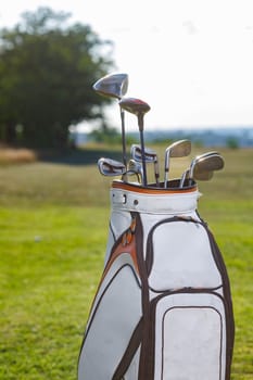 Golf clubs drivers over green field background.