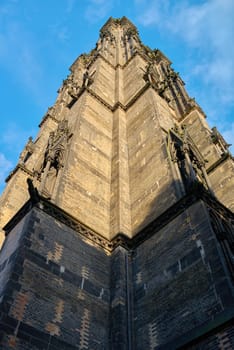 Black burnt spire of the Gothic Revival church of St. Nicholas Cathedral in Hamburg against the background of the dark sky