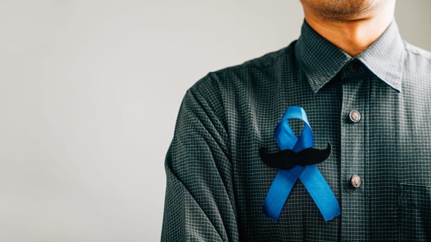 Men's hands reveal a Blue Ribbon with a moustache, symbolizing their commitment to awareness for Colon cancer, Colorectal cancer, Child Abuse, world diabetes day, and International Men's Day.