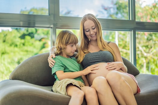 A heartwarming moment: pregnant mother and her older son sit on the sofa, engaging in a tender conversation about the upcoming pregnancy.