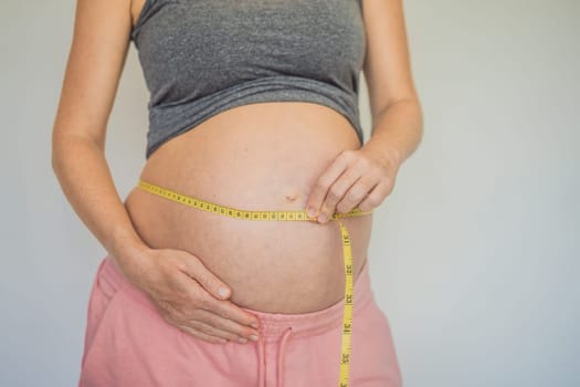 Young woman measuring her pregnant belly with centimeter tape. Centimeters European standard. Preparation for childbirth, Girl big belly advanced healthy pregnancy.