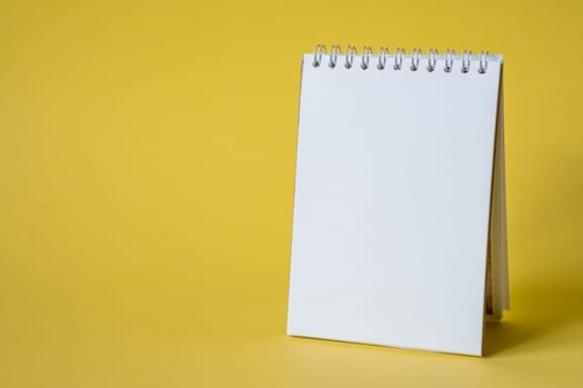 Opened notepad on a yellow background. Composition of writing to-dos for the day. The notebook lies on a plain background with space for writing.