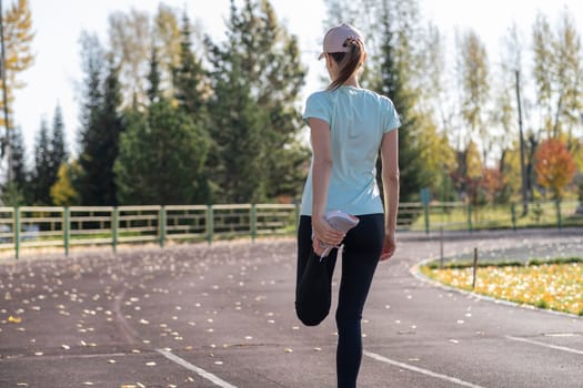 A young beautiful woman in sportswear plays sports at a local stadium. Exercise, jog and exercise at the beginning of the day. Healthy and active lifestyle.