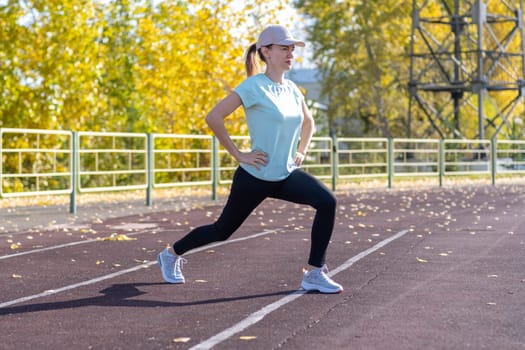 A young beautiful woman in sportswear plays sports at a local stadium. Exercise, jog and exercise at the beginning of the day. Healthy and active lifestyle.