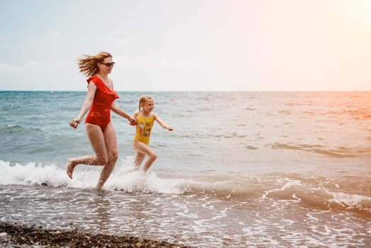 Happy loving family mother and daughter having fun together on the beach. Mum playing with her kid in holiday vacation next to the ocean - Family lifestyle and love concept.