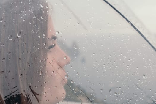 Woman rain park. Happy woman portrait wearing a raincoat with transparent umbrella outdoors on rainy day in park near sea. Girl on the nature on rainy overcast day