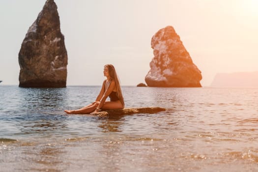 Woman travel sea. Young Happy woman in a long red dress posing on a beach near the sea on background of volcanic rocks, like in Iceland, sharing travel adventure journey