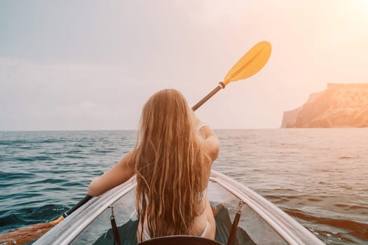 Woman in kayak back view. Happy young woman with long hair floating in transparent kayak on the crystal clear sea. Summer holiday vacation and cheerful female people having fun on the boat.