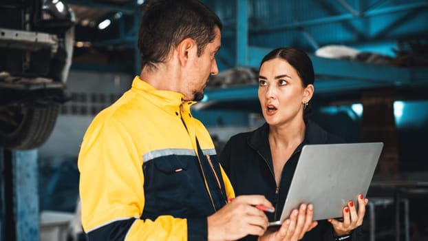 Two vehicle mechanic working together, conduct car inspection with laptop. Automotive service technician in uniform carefully make diagnostic troubleshooting to identify error. oxus