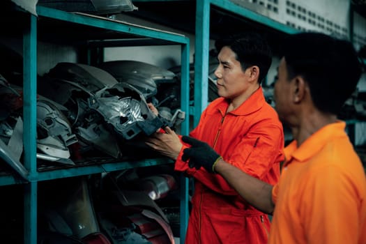 Mechanic worker inspect spare vehicle parts stored in inventory at automotive service. Reusing car components, optimizing resource and availability of spare part for repair and maintenance. Oxus