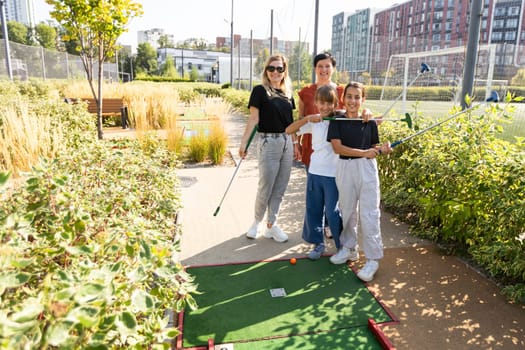 Group of smiling friends enjoying together playing mini golf in the city. High quality photo