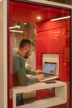 A bearded man in a booth for online negotiations. Privacy booth