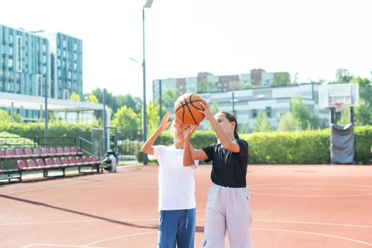 Children and sports. Teenage girl playing basketball on the playground. High quality photo