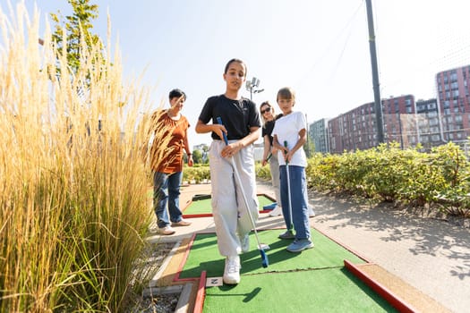 family playing mini golf on a cruise liner. Child having fun with active leisure on vacations. High quality photo