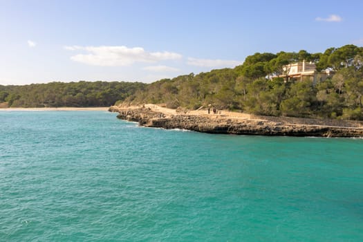 Coastal landscape with a point jutting into turquoise waters under clear skies, cala mondrago, mallorca, balearic island, spain,