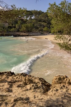 Serene beach with gentle waves and sandy shore surrounded by trees, cala mondrago, mallorca, balearic island, spain,