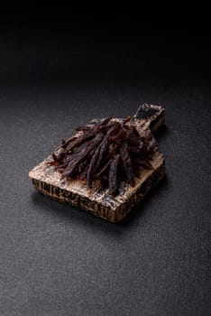 Jerky, dried horse meat or beef slices with salt and spices on a dark concrete background
