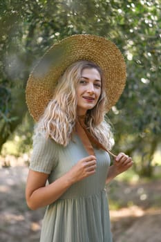 Blonde woman in a straw hat near olive tree in garden in Provence, France