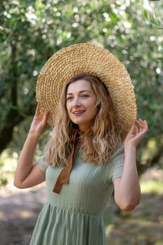 Blonde woman in a straw hat near olive tree in garden in Provence, France