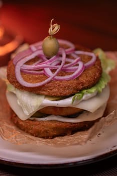 Juicy burger made from draniki and meat patties, lettuce, onion on top and olive. A delicious photo for a menu, culinary website, or an advertisement for catering establishments.