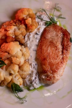 Baked turkey and cauliflower are a delicious dish on the menu at the restaurant. A beautiful and delicious photo for a menu, culinary website, or an advertisement for catering establishments.